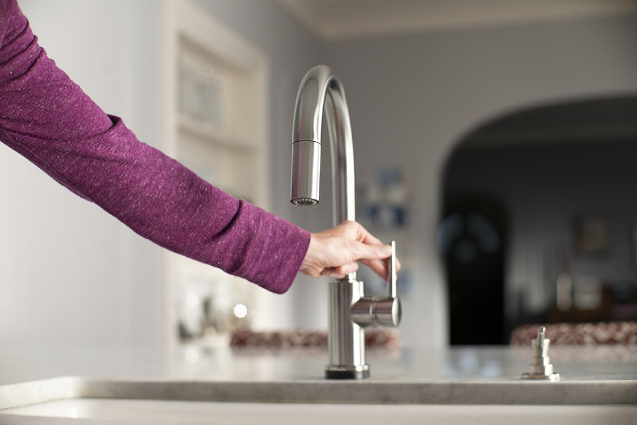 A hand showing that the faucet can also be turned on in the traditional way (versus motion or tap activated).